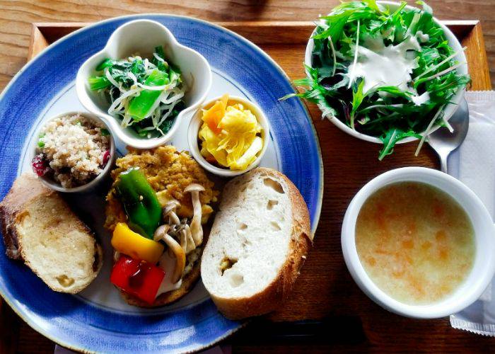 A top-down shot of vegan dishes at cafe SPROUTS, including a vegetable soup, pickled vegetables and more.